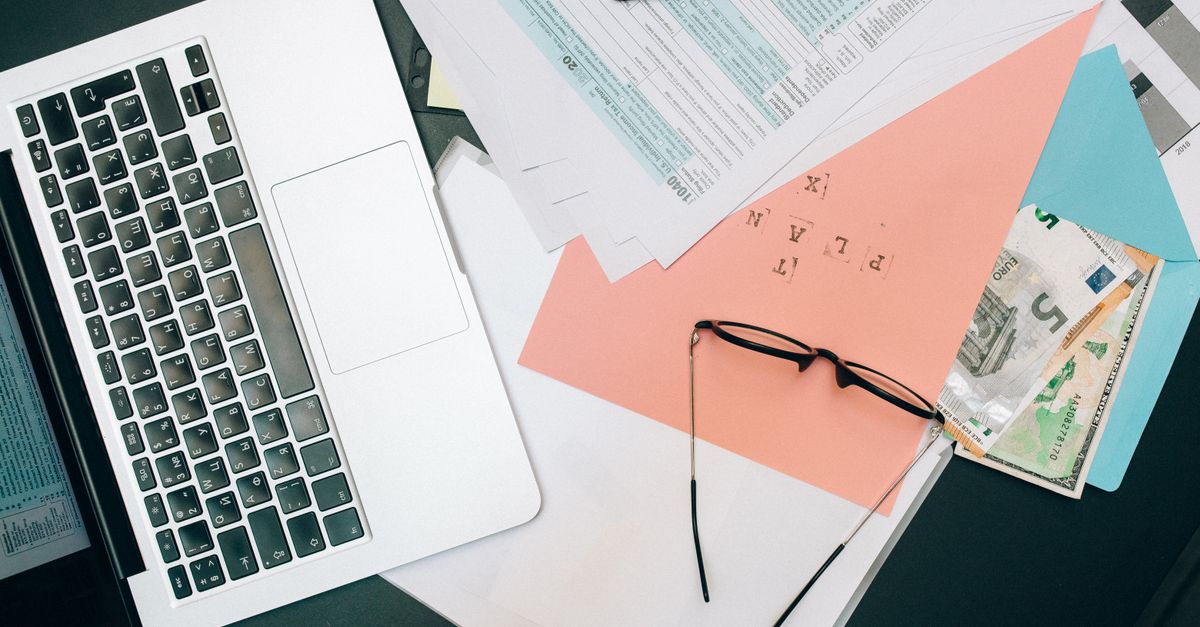 A tidy workspace featuring a laptop, documents, and eyeglasses for productivity.