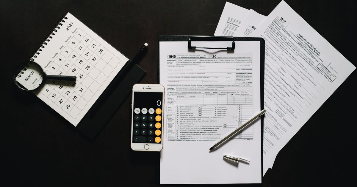 Flat lay of financial tools for tax preparation including forms, calculator, and calendar.
