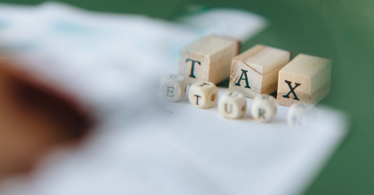Wooden blocks and dice spelling 'Tax Return' on a blurred green background.
