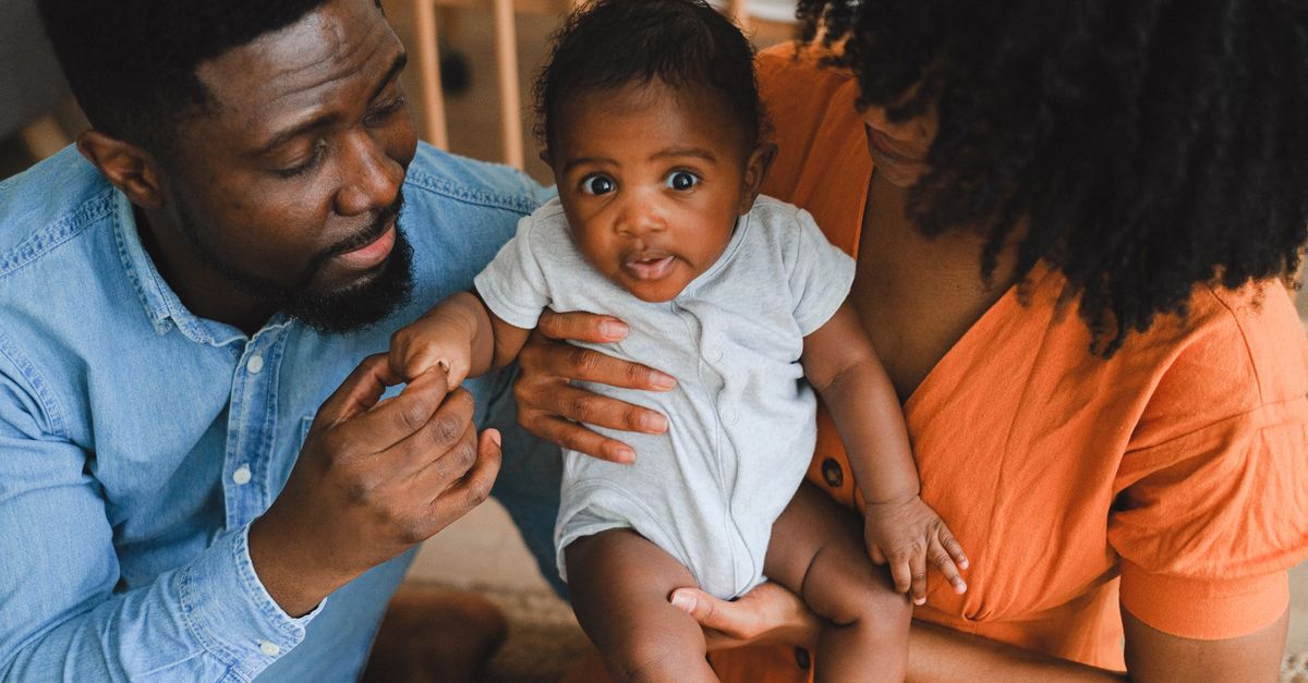 Loving parents holding adorable baby in a warm, intimate home environment.