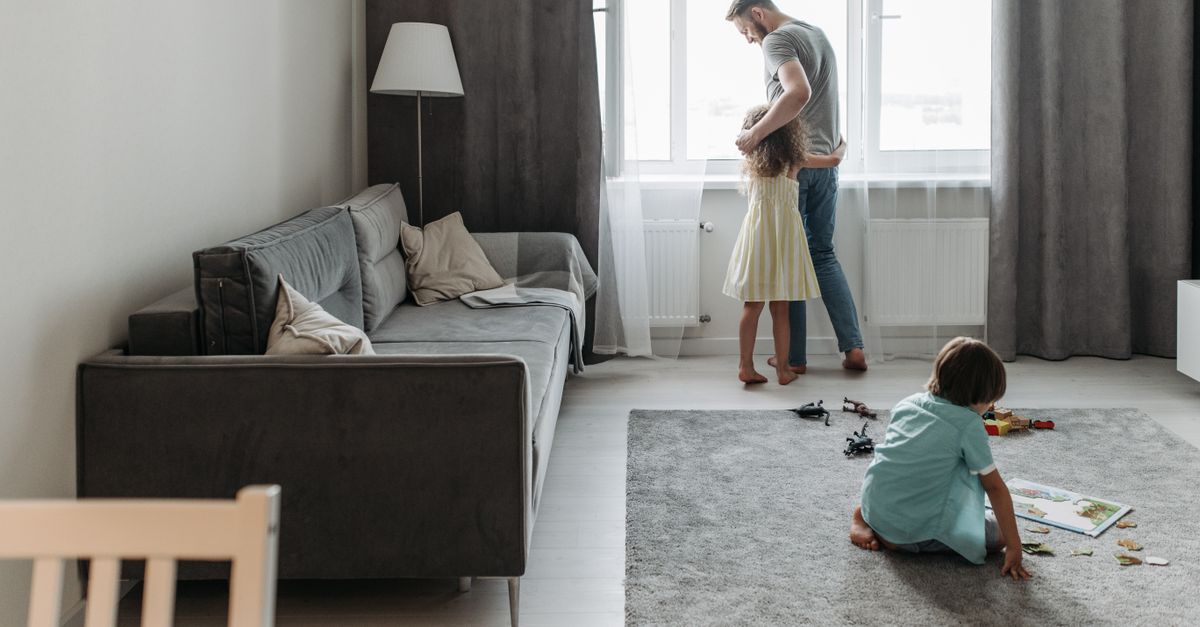A father bonding with his children in a bright, modern living room setting.