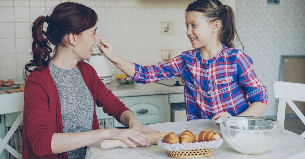 Joyful mother and daughter baking at home, sharing a fun and intimate moment.