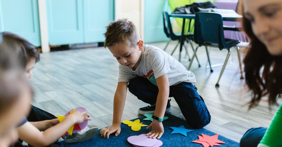 Children playing with colorful shapes in a classroom setting, fostering creativity and learning.