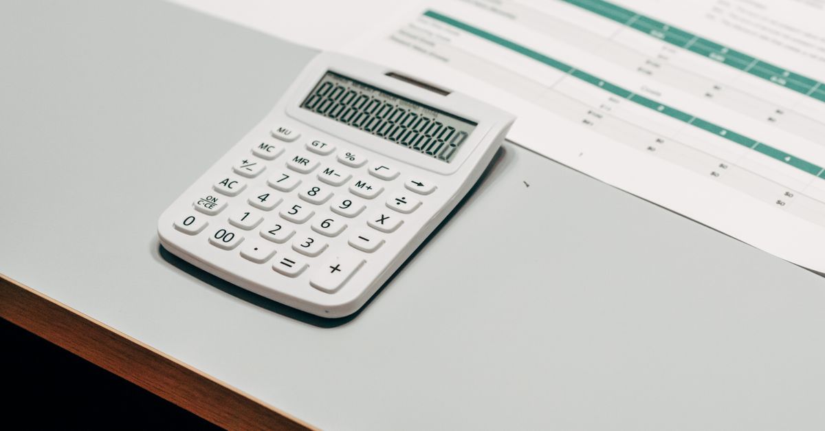 Close-up of a white calculator next to a financial spreadsheet on a desk.